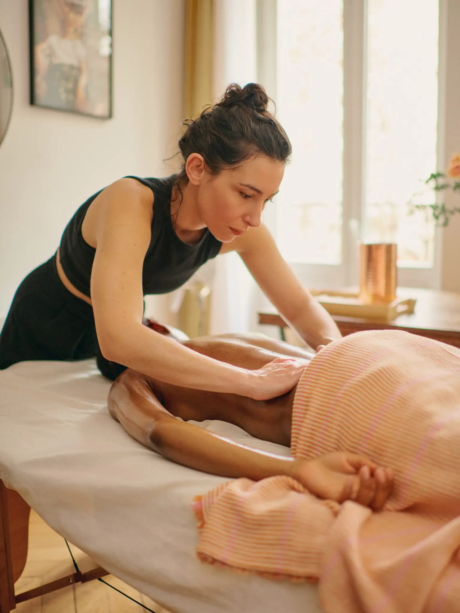 Clémence penchée sur une cliente pendant un massage, concentrée