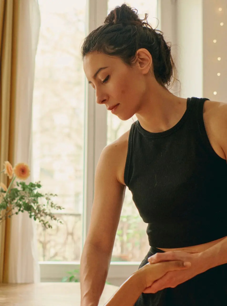 Clémence, concentrée, une main posée sur le bras d’une cliente, devant une grande fenêtre lumineuse