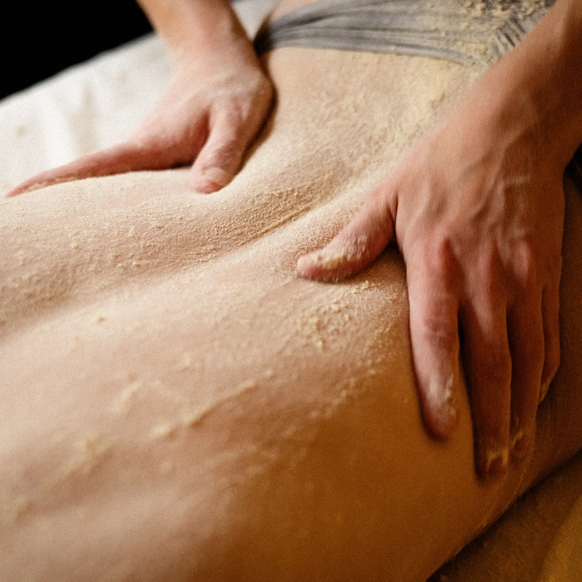 Massage Udvartana : mains sur un dos recouvert de farine de pois chiche
